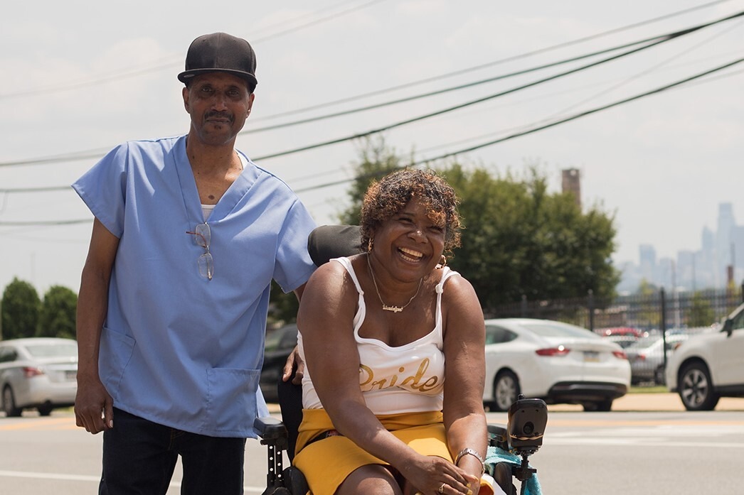 Caregiver posing with smiling woman in wheelchair