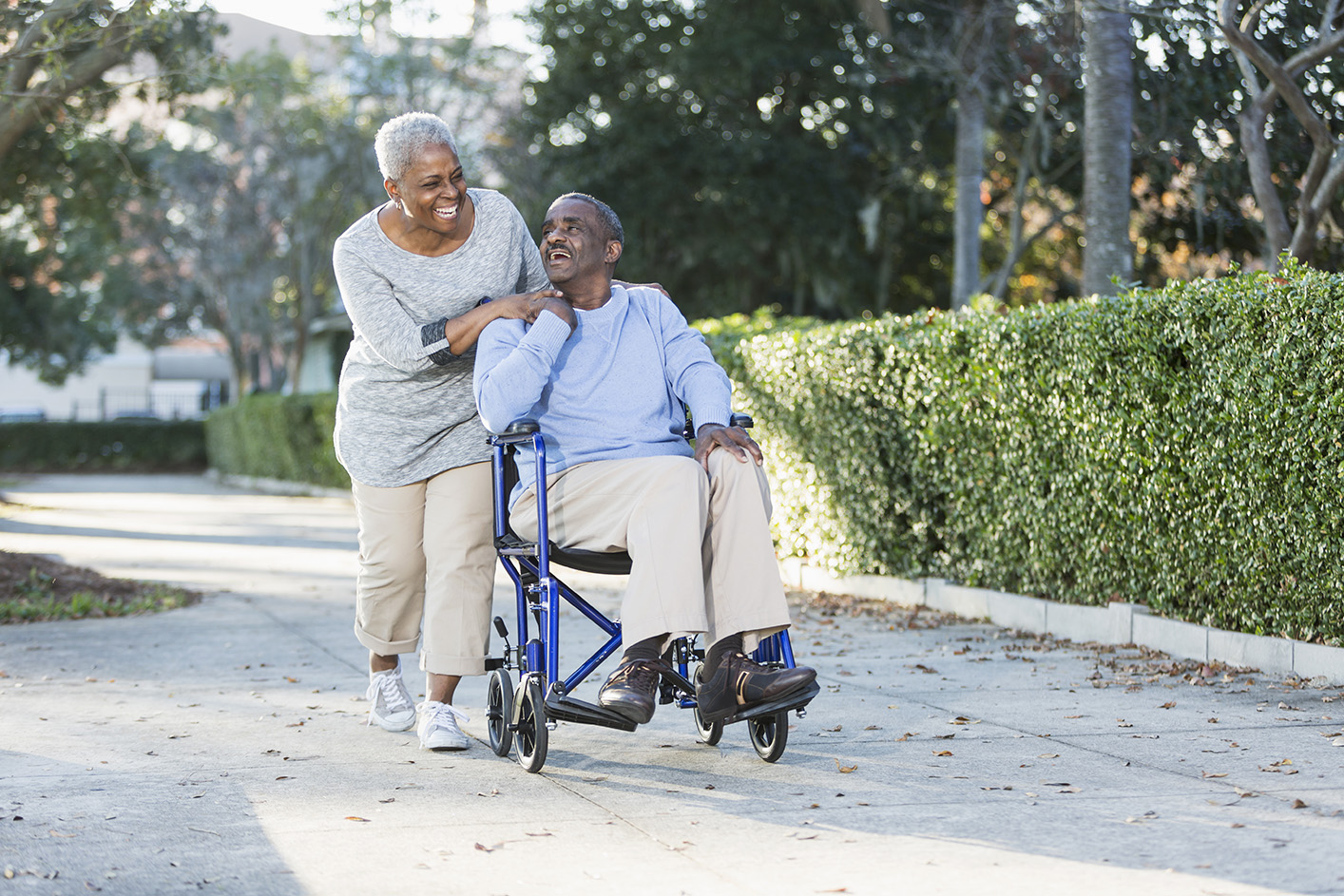 Caregiver lauging with client as she pushes him in wheelchair