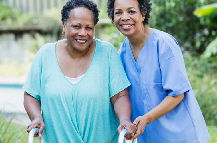 Caregiver helping older woman using walker