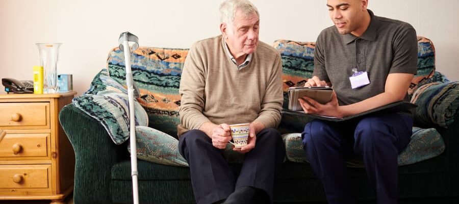 A caregiver talks with a man in his home