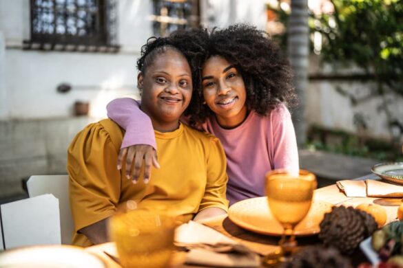 Caregiver with arm around person with disability sitting at table