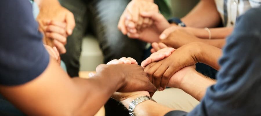 Closeup of people holding hands together during support group meeting