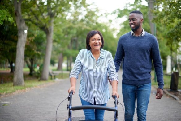 Woman using walker walking with caregiver