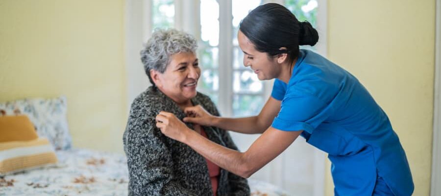 Caregiver assisting senior citizen with getting dressed for the day