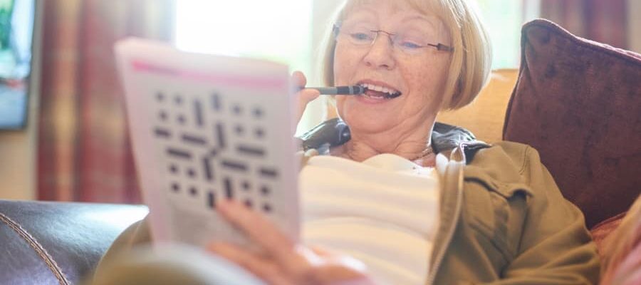 Older person on couch doing crossword puzzle